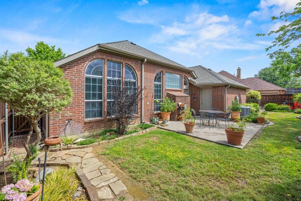 Expansive backyard featuring a manicured lawn, a large concrete patio, and a flagstone pathway