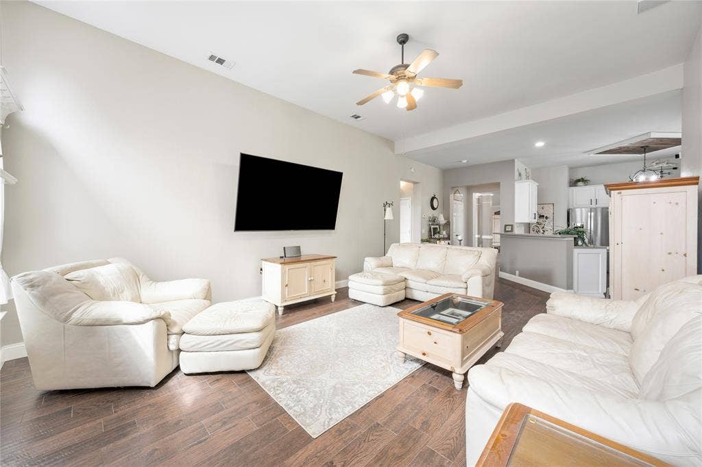 Spacious living area featuring wood-finish flooring, vaulted ceilings, and a ceiling fan
