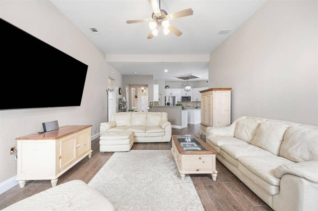 Spacious living area featuring wood-finish flooring, vaulted ceilings, and a ceiling fan