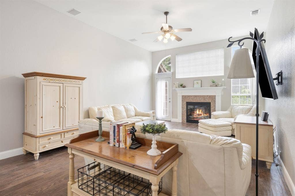 Spacious living area featuring wood-finish flooring, a fireplace with a stone surround, and an arched transom window