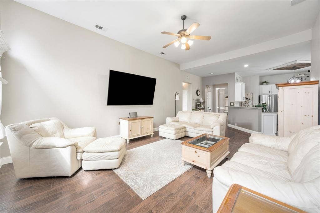 Spacious living area featuring wood-finish flooring, vaulted ceilings, and a ceiling fan