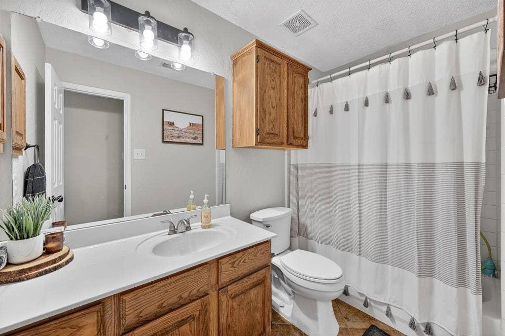 Bathroom featuring a wood-finish vanity with an integrated white sink, a chrome two-handle faucet, and a large wall-mounted mirror