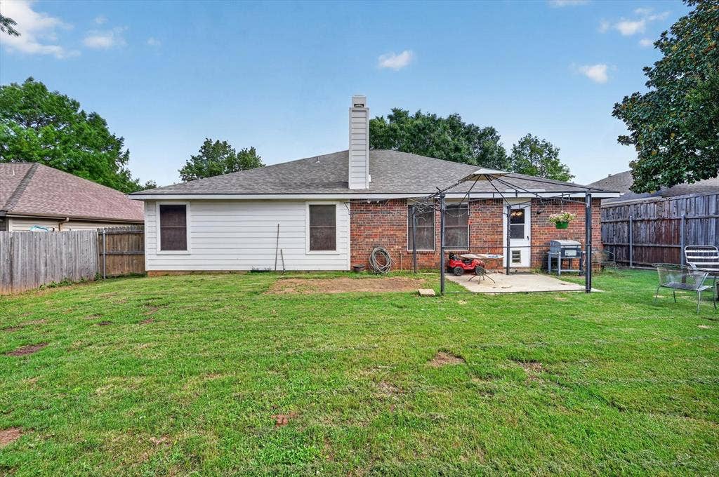 Expansive backyard featuring a brick and siding exterior, a concrete patio, and a privacy fence