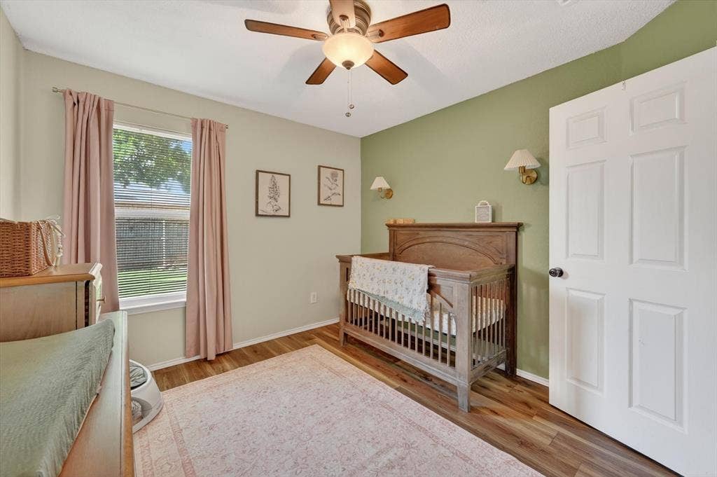 Interior room featuring wood-finish flooring, a ceiling fan with integrated lighting, and a paneled white door