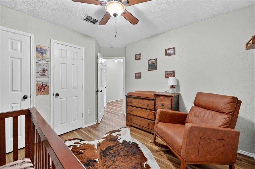 Hallway featuring wood-finish flooring, light gray walls, white paneled doors, and a ceiling fan with integrated lighting