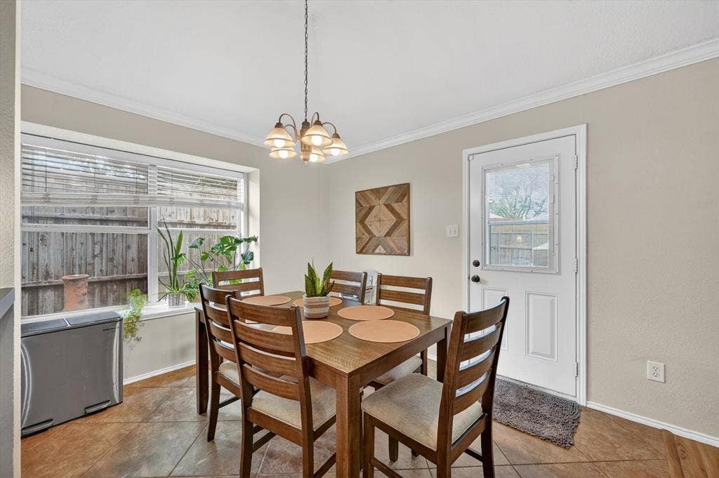 Dining space featuring a multi-pane window with blinds, a white paneled door with an upper window, a central chandelier, and tile flooring