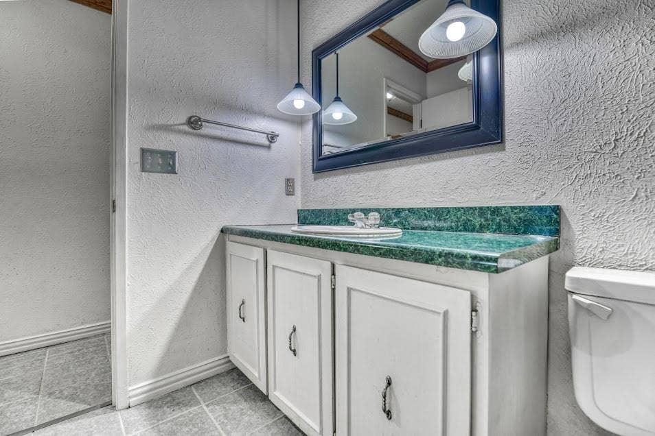 White vanity with panel-front cabinetry, a drop-in sink, and a green patterned countertop
