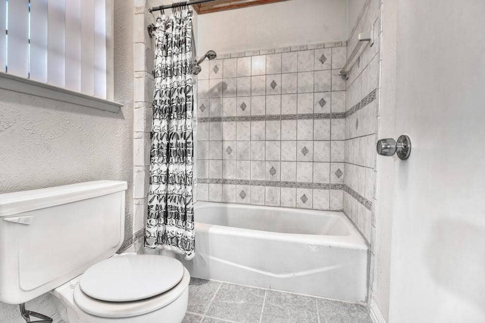 White tile-surround bathtub and shower with patterned accent tiles