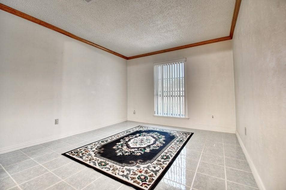 Ceramic tile flooring, crown molding, and a window with vertical blinds