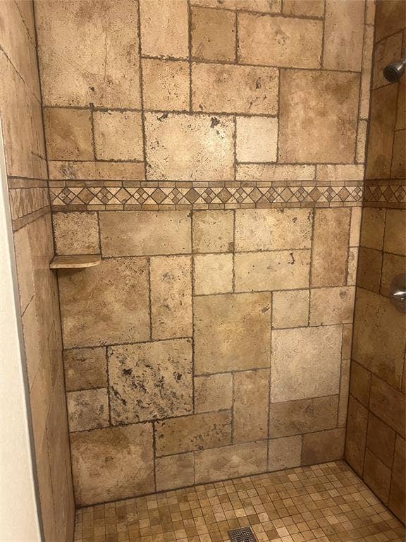 121 Brookside Drive, Duncanville, TX 75137 Shower enclosure featuring a mosaic tile border, integrated wall shelf, and coordinating floor tiles