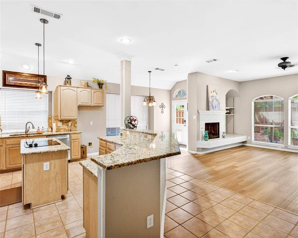6005 Pin Oak Drive, McKinney, TX 75072 Spacious open-concept interior featuring a kitchen with light wood cabinetry, granite countertops, and a tile backsplash