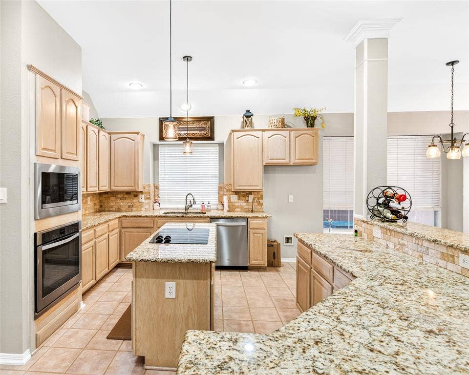 6005 Pin Oak Drive, McKinney, TX 75072 Kitchen featuring granite countertops, light wood-finish cabinetry, stainless steel appliances, a center island with cooktop, and tile flooring