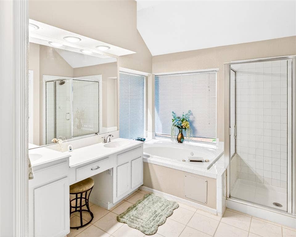 6005 Pin Oak Drive, McKinney, TX 75072 Bathroom featuring a built-in soaking tub, separate glass-enclosed shower, dual vanity with integrated sinks, and ample natural light