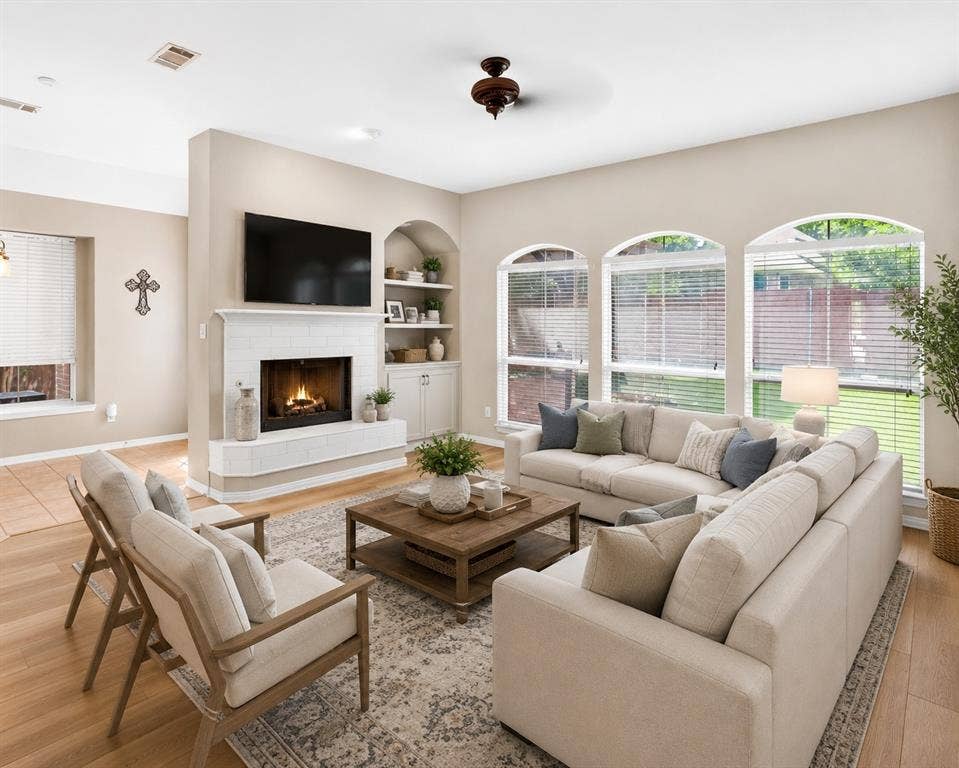6005 Pin Oak Drive, McKinney, TX 75072 Living area featuring a tiled fireplace with mantel, built-in shelving, and multiple arched windows