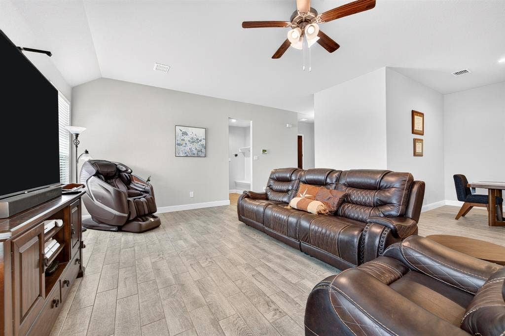 829 Poppie Lane, Midlothian, TX 76065 Spacious living area featuring wood-finish flooring, vaulted ceilings, and a ceiling fan with integrated lighting