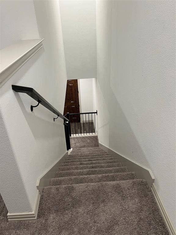 6041 Roper Road, McKinney, TX 75070 Carpeted staircase featuring a dark handrail with black iron balusters