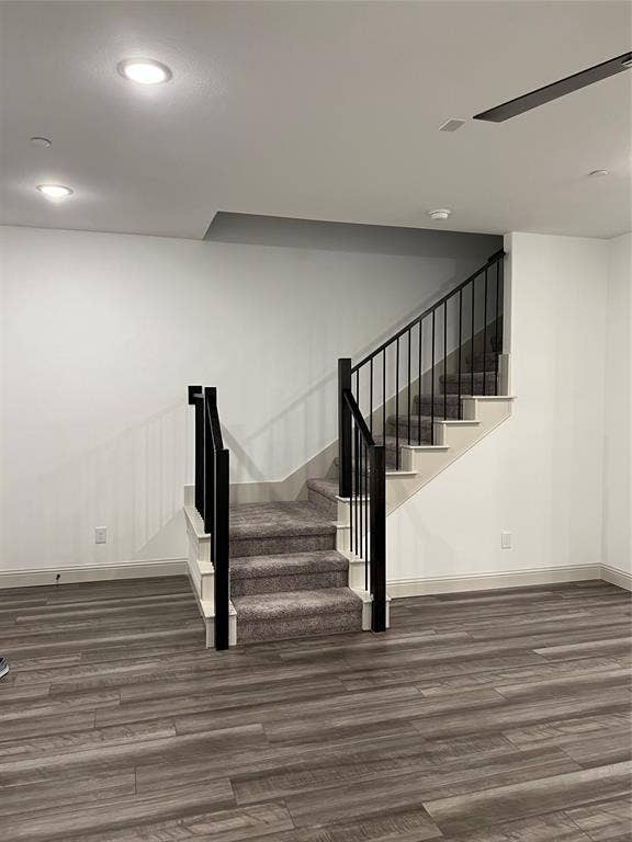 6041 Roper Road, McKinney, TX 75070 Staircase featuring dark carpet treads, white risers, and black metal balusters