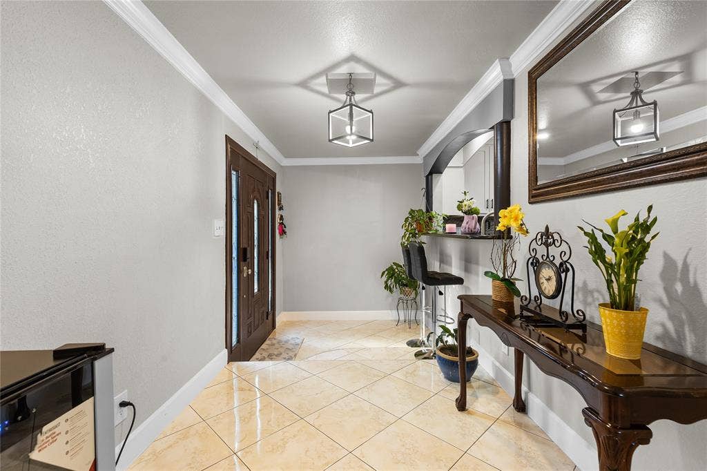 Entryway featuring a dark wood paneled door with sidelights, tile flooring, crown molding, and a contemporary ceiling fixture
