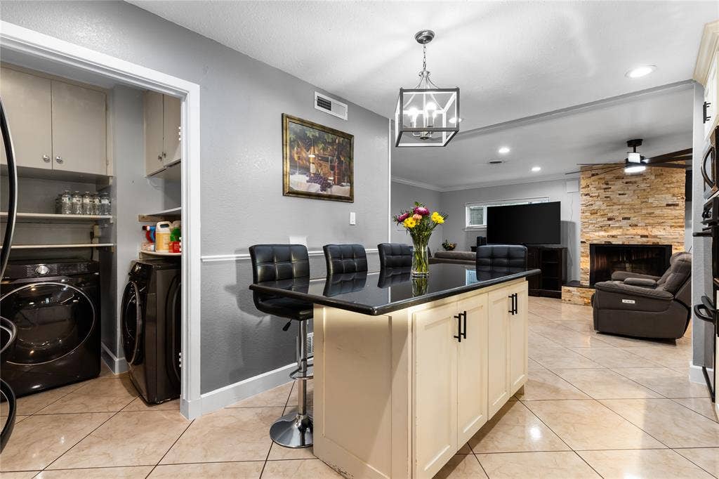 Kitchen island with dark countertop, pendant lighting, recessed lighting, and tile flooring