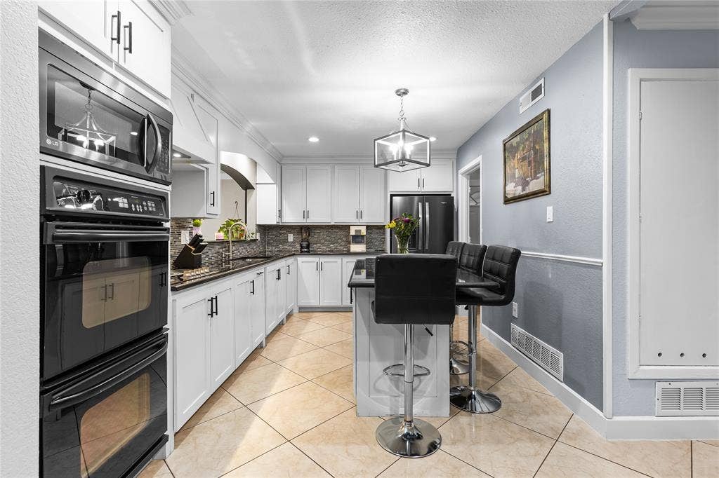 Kitchen featuring white cabinetry with dark hardware, dark countertops, a built-in double oven, and tiled flooring