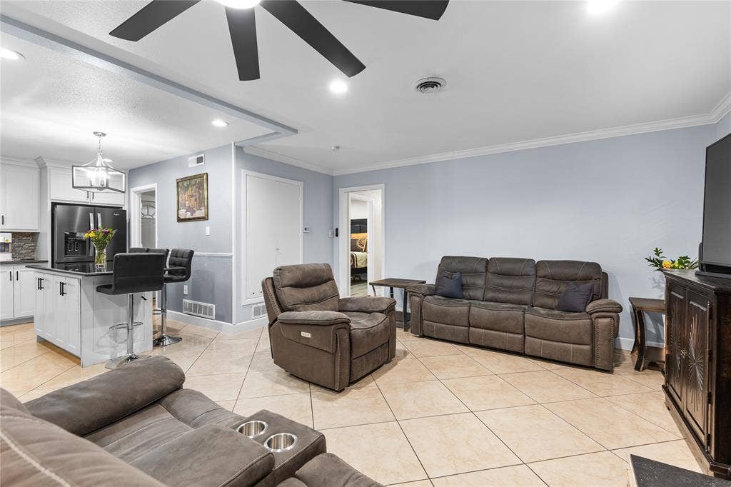 Open concept living area featuring light blue walls, tile flooring, and a contemporary ceiling fan