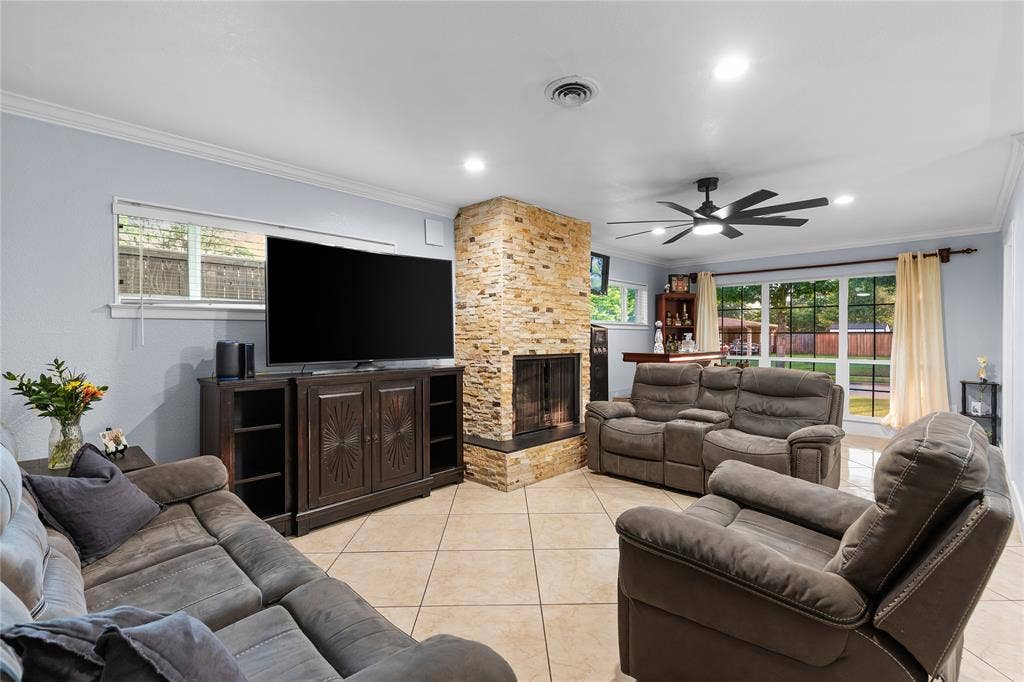 Living area featuring a floor-to-ceiling stacked stone fireplace, tile flooring, and multiple windows