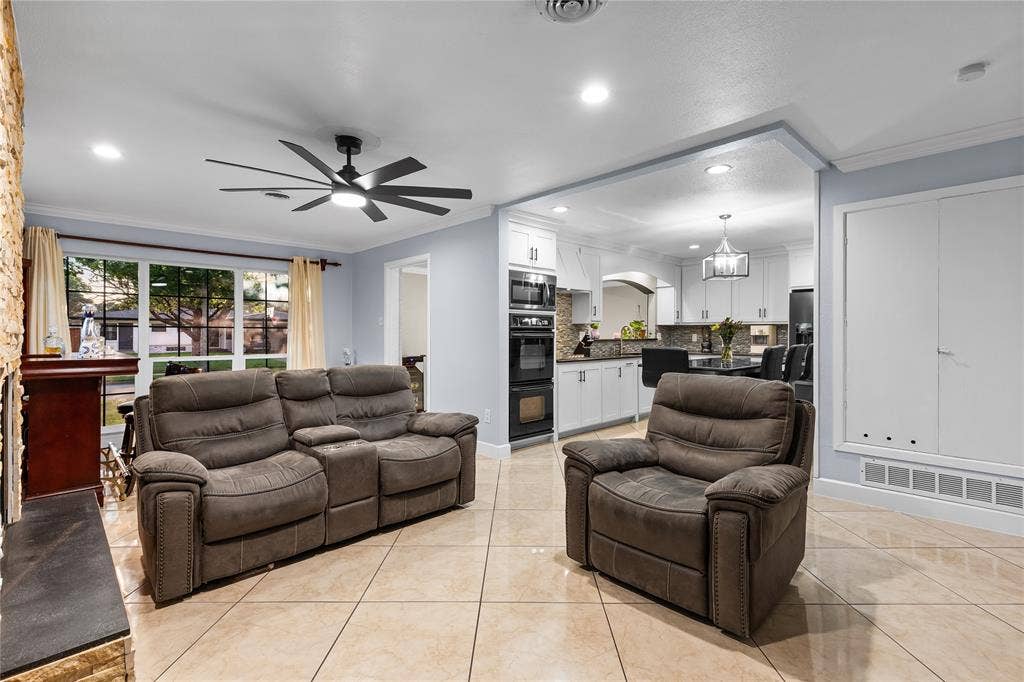Open-concept living area featuring neutral tile flooring, a stone-clad fireplace surround, and recessed lighting