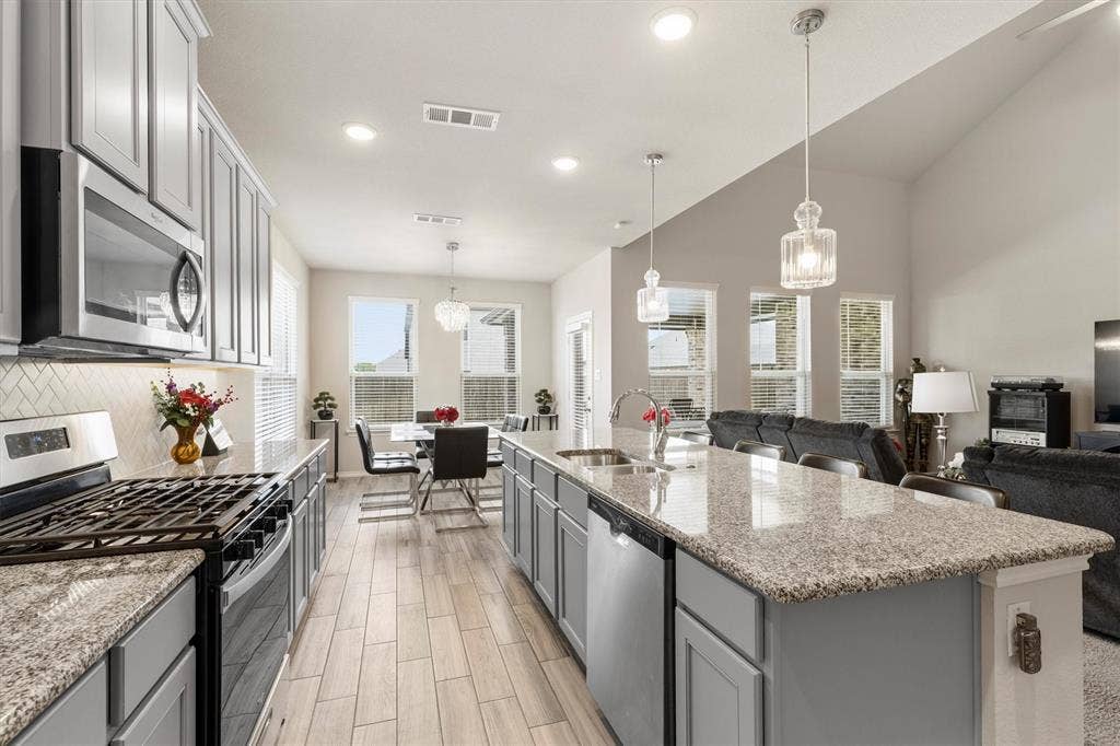 702 Matador Lane, Arlington, TX 76002 Modern kitchen featuring light gray cabinetry, stainless steel appliances, speckled stone countertops, and a subway tile backsplash