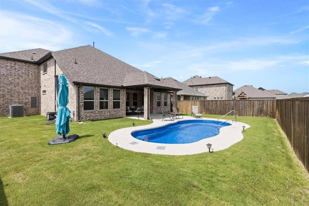 702 Matador Lane, Arlington, TX 76002 Backyard featuring an in-ground swimming pool with a concrete surround, an extended covered patio, and a private wooden fence
