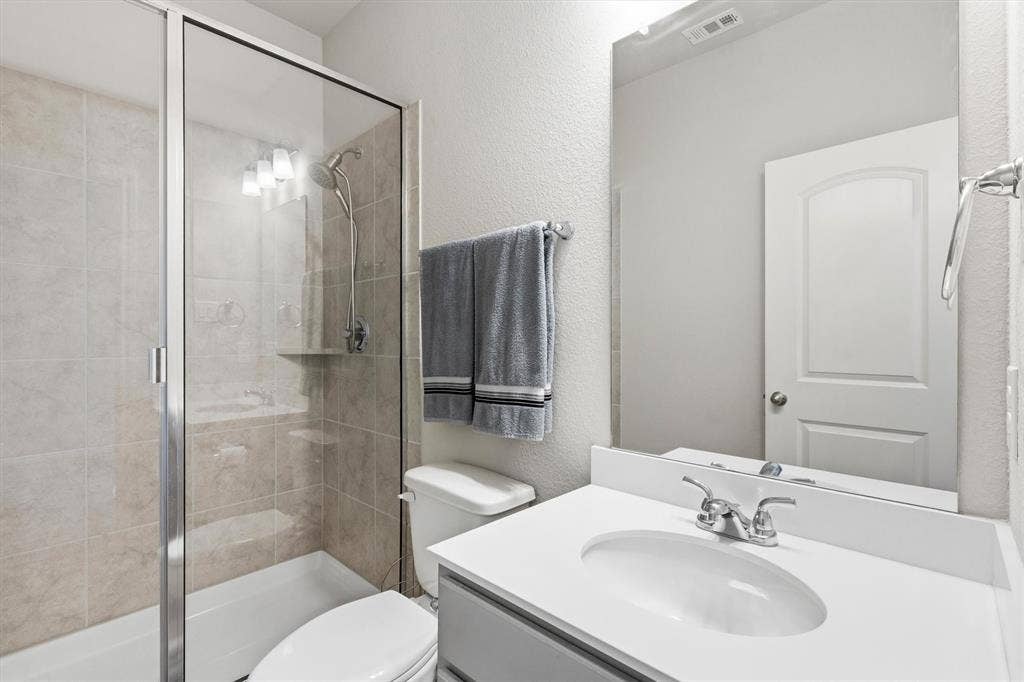 702 Matador Lane, Arlington, TX 76002 Bathroom featuring a glass-enclosed shower with subway tile surround, white bathtub, single vanity with integrated sink, and chrome fixtures
