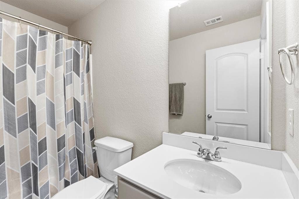 702 Matador Lane, Arlington, TX 76002 Bathroom featuring a single vanity with an integrated sink, polished chrome faucet, and a large wall-mounted mirror