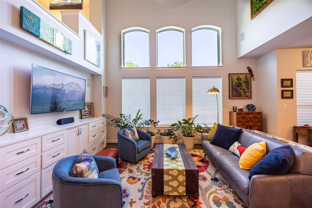 Spacious living area featuring high ceilings, a wall of arched windows, and extensive built-in cabinetry with ample storage