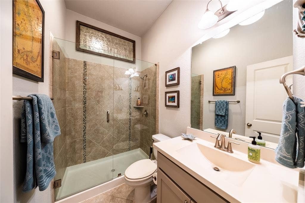 Downstairs bathroom featuring a glass-enclosed shower with tile surround, a single vanity with an integrated sink