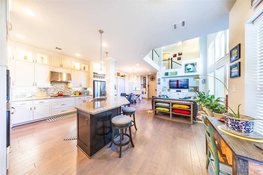 Open-concept living area featuring light wood-finish flooring, a two-story ceiling, and extensive natural light