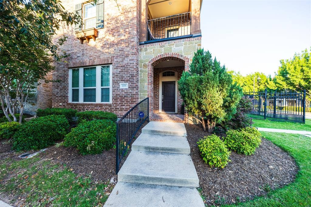 View of covered porch entry from sidewalk, with landscaped flower beds provided by HOA.