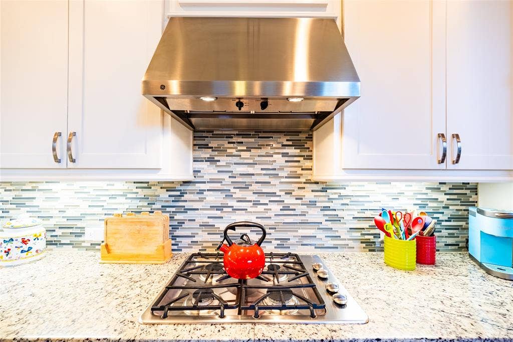 Stainless steel range hood above a gas cooktop