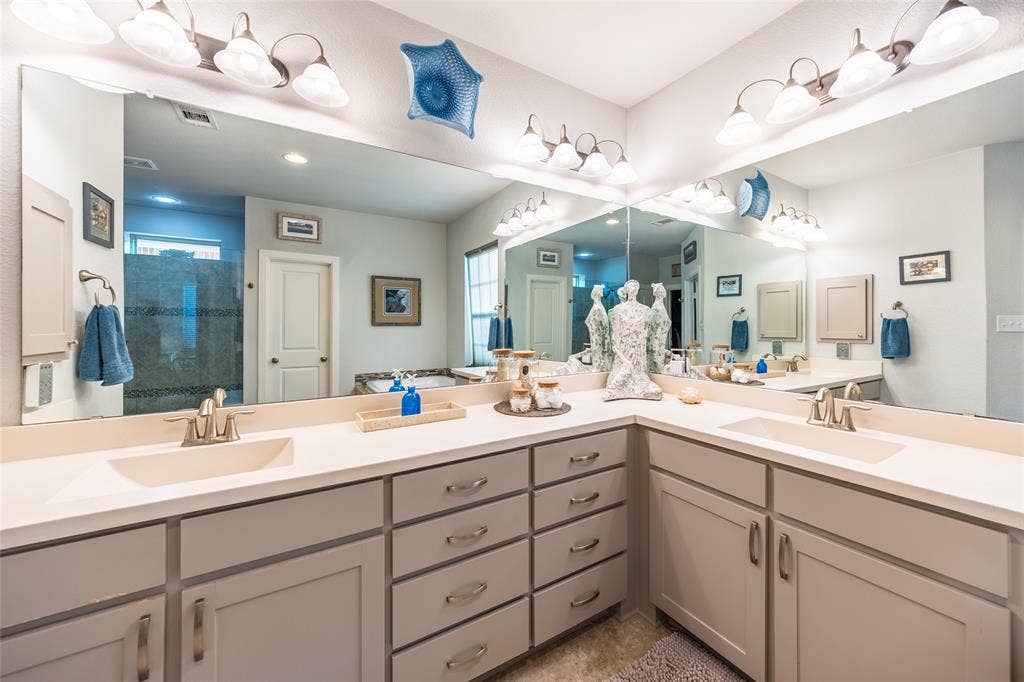 Spacious primary suite bathroom featuring an expansive vanity with double sinks, light-toned countertops, and ample storage with soft-close drawers and cabinets.