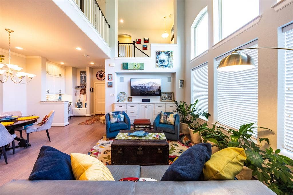 Spacious living area viewed from entry way and showing an upper-level balcony with white balusters