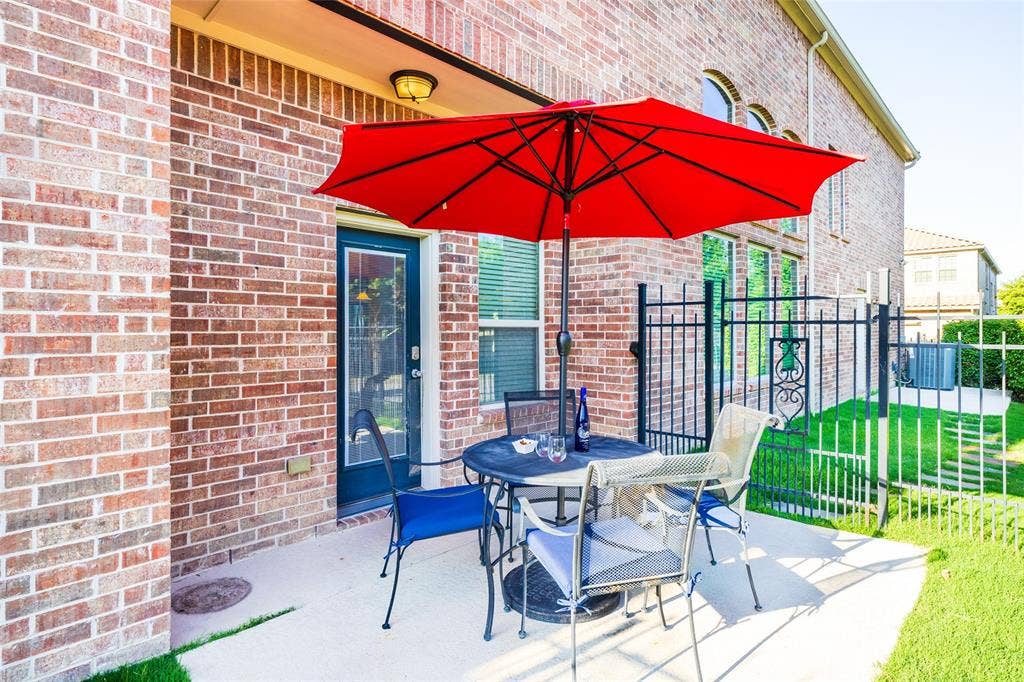 Private patio with concrete surface, red brick exterior, and a black wrought iron.