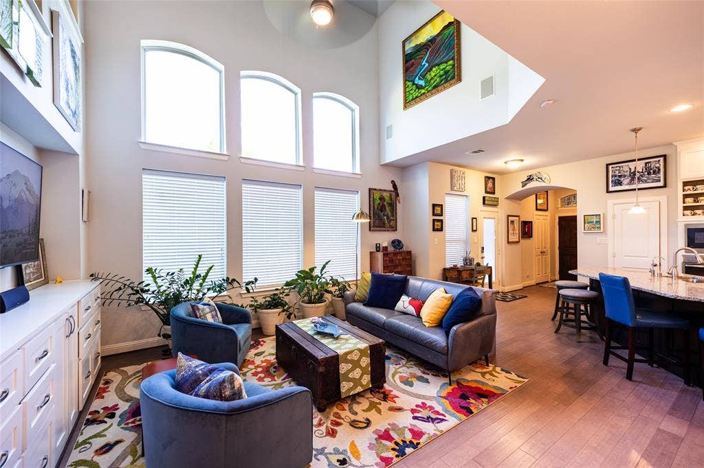 Living area featuring a soaring vaulted ceiling, a bank of tall arched windows, and wood flooring