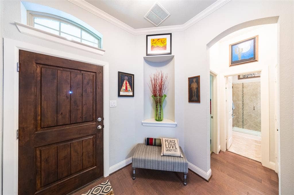 Entryway featuring solid wood ash door with an arched transom window and hardwood flooring, a recessed wall niche, and crown molding