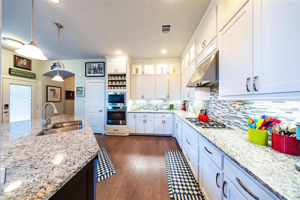 Spacious kitchen featuring white cabinetry, light-colored countertops, and wood flooring