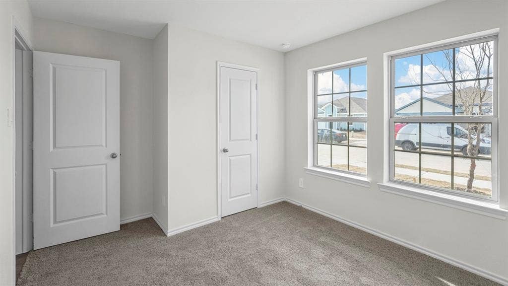 1953 Freeman Street, Tyler, TX 75704 Bright room with two white-framed windows, neutral carpet flooring, and two interior doors with silver hardware