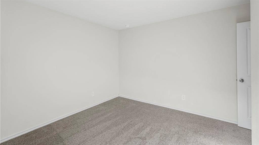 1953 Freeman Street, Tyler, TX 75704 Interior room featuring light gray wall paint, gray carpet flooring, white baseboards, and a white door with a polished chrome knob
