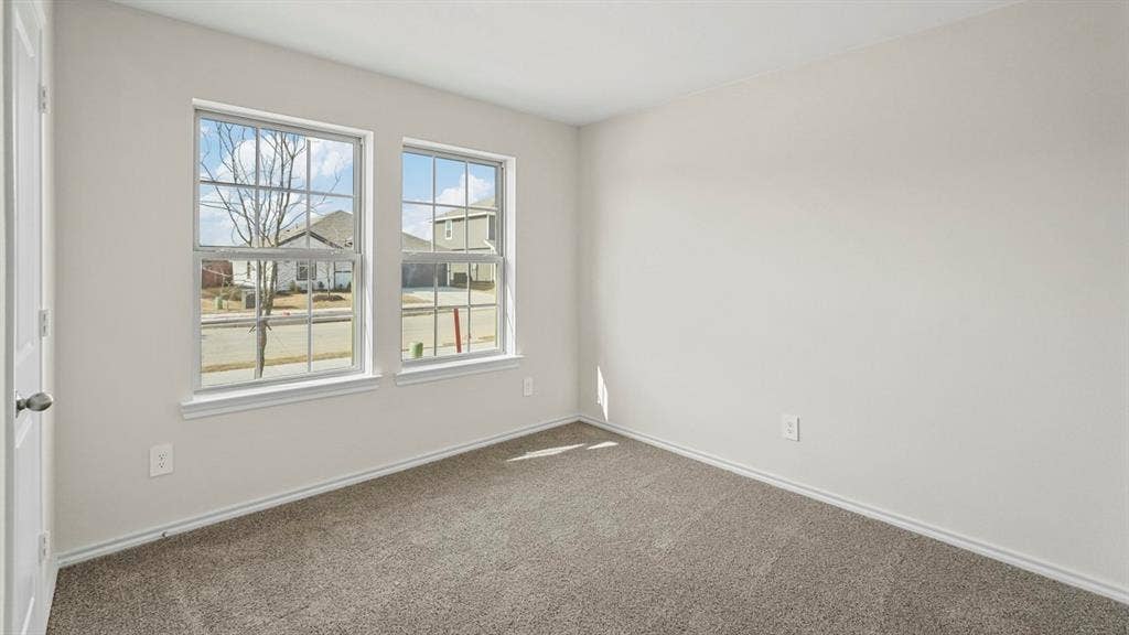 1953 Freeman Street, Tyler, TX 75704 Bright room featuring two double-hung windows with white trim, light gray wall paint, and gray carpet flooring