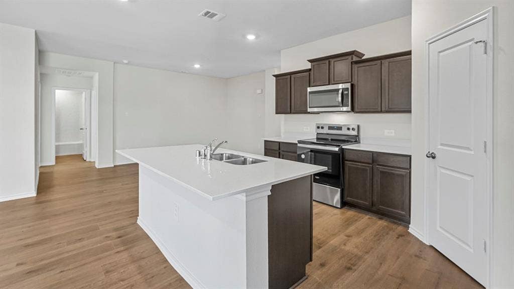 1953 Freeman Street, Tyler, TX 75704 Contemporary kitchen with wood-finish flooring, white quartz countertops, stainless steel appliances, dark wood cabinetry, and recessed lighting