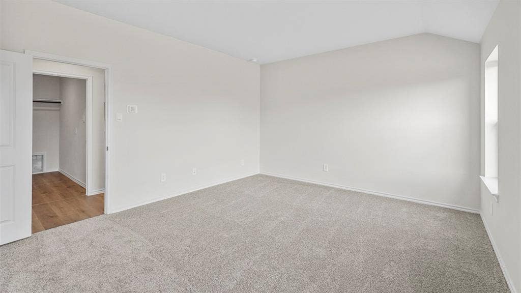 1953 Freeman Street, Tyler, TX 75704 Spacious room featuring light-colored carpeting, a vaulted ceiling, and a large window