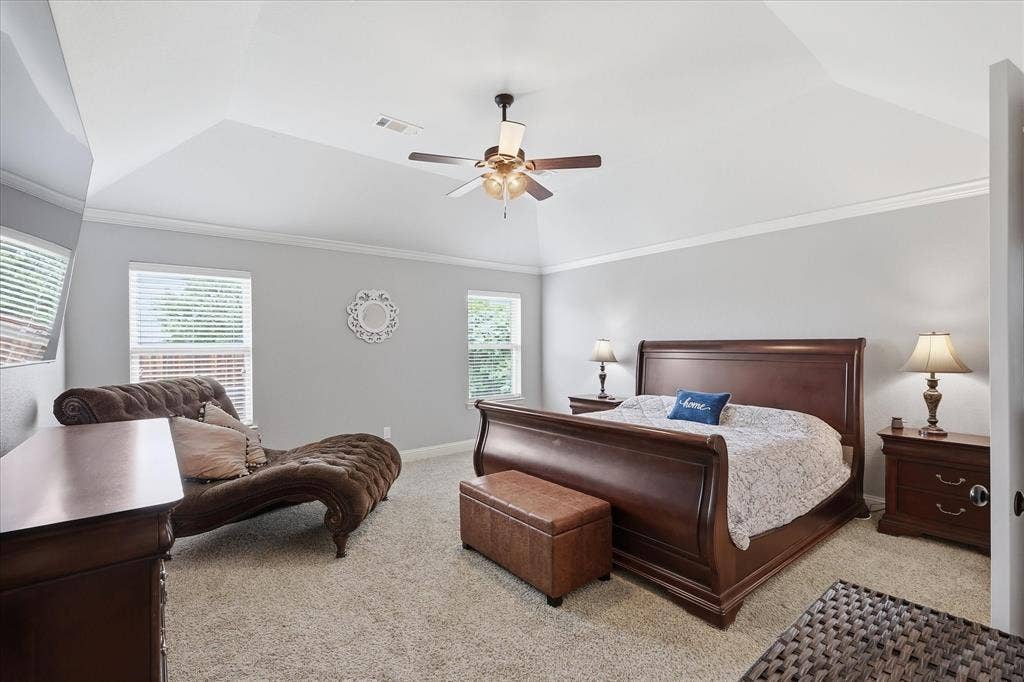 Carpeted interior space featuring a tray ceiling, crown molding, and a ceiling fan with light fixture