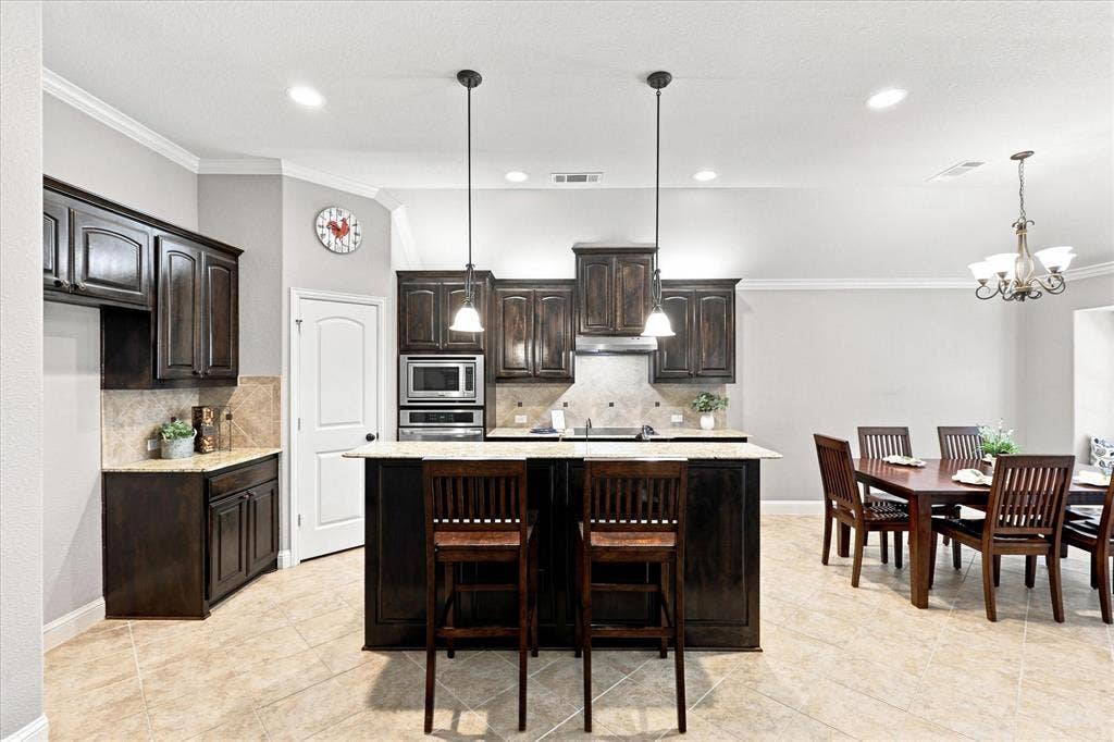 Kitchen featuring dark wood cabinetry, light-toned countertops, and a tile backsplash