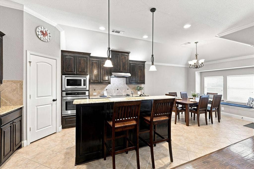 Kitchen featuring dark wood-finish cabinetry, stainless steel appliances, stone countertops, and tile flooring
